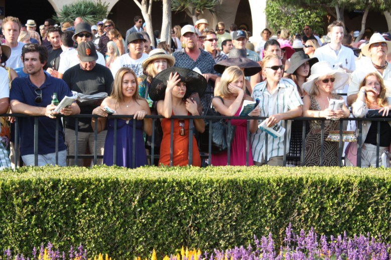 Rail birds crowd the paddock fence to get a look at the horses before the Opening Day nightcap